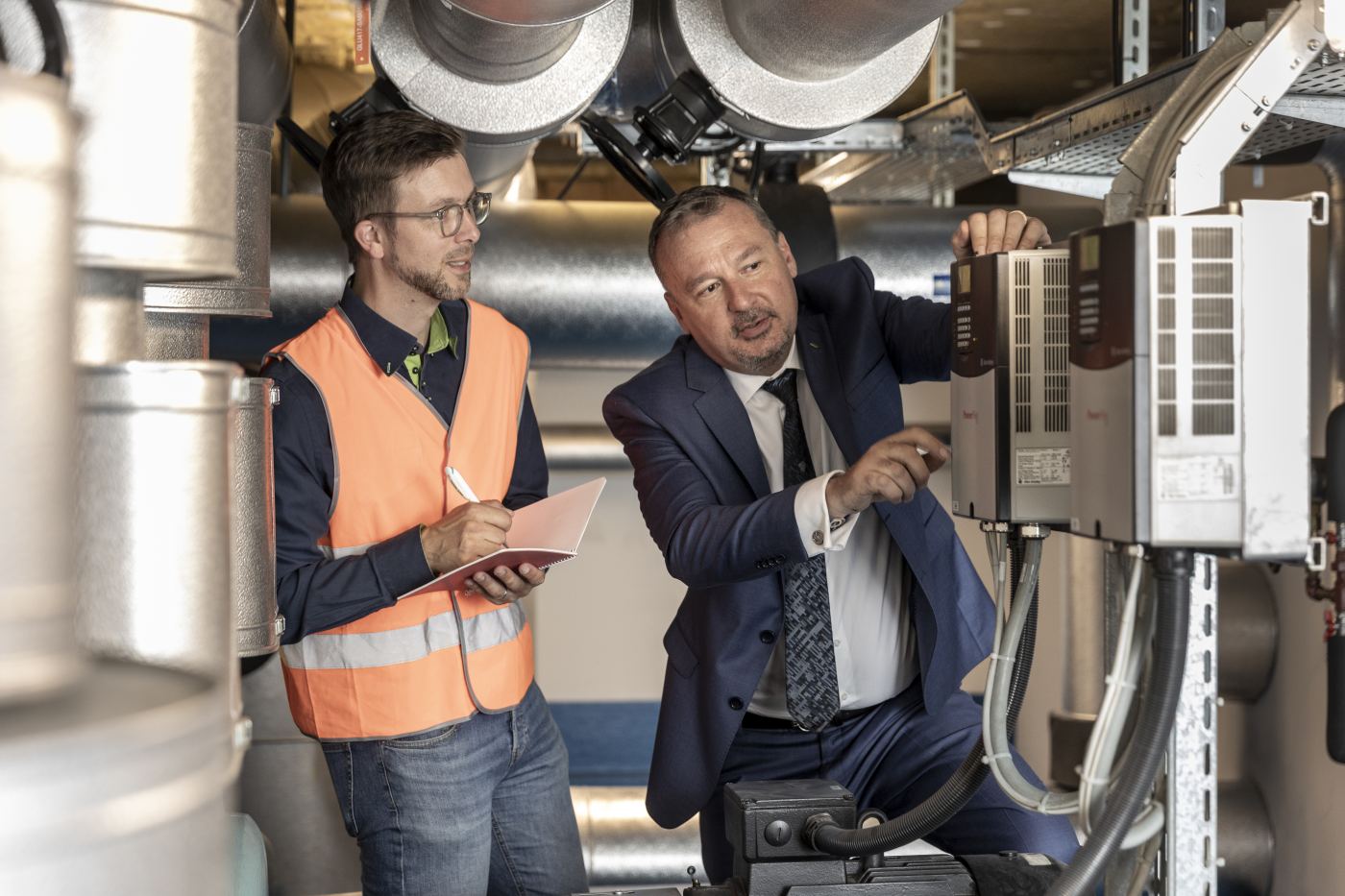 Frédéric Foulon und der act-Energiespezialist stehen vor einer technischen Anlage